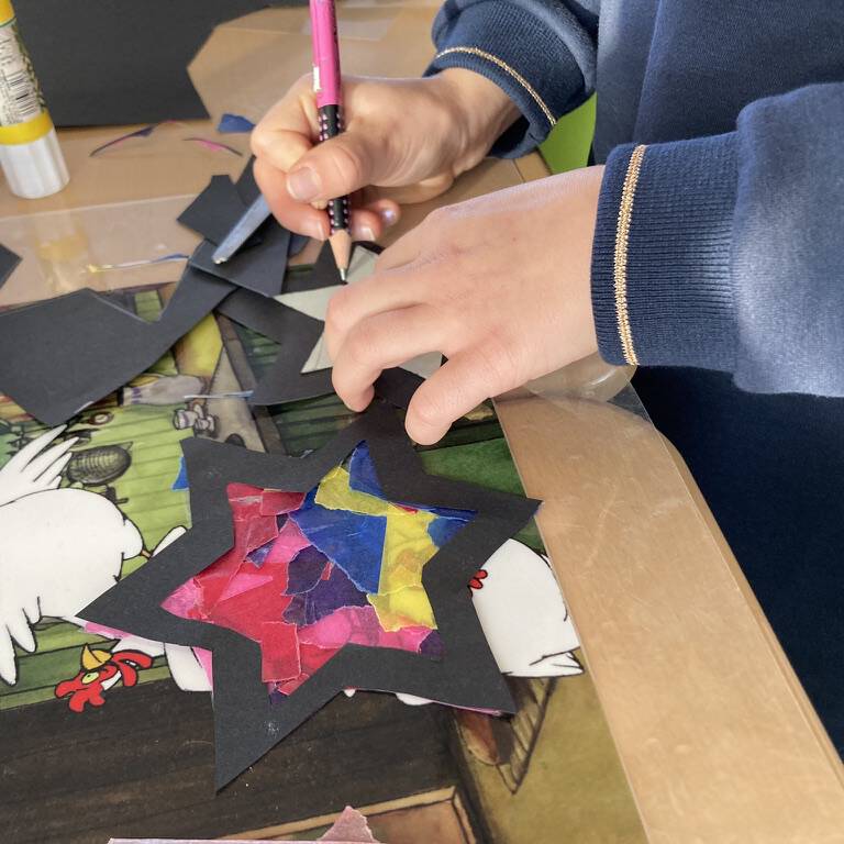 Kinderhand malt einen schwarzen Stern mit Bleistift