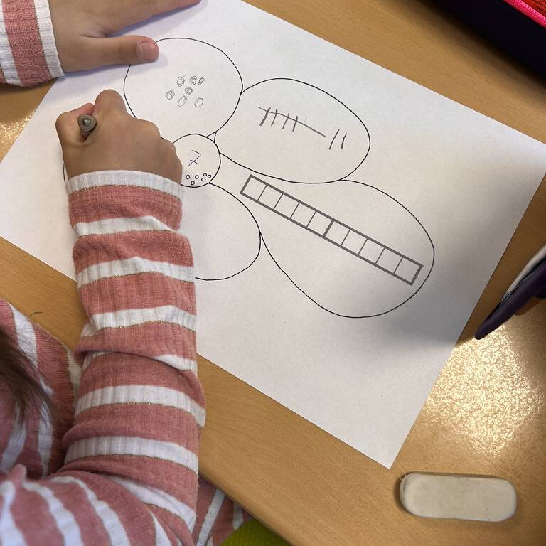 Kinderhand malt mehrere Kreise mit Stift auf weißem Papier