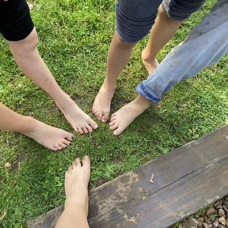 Füße auf einem Rasen sternförmig angeordnet