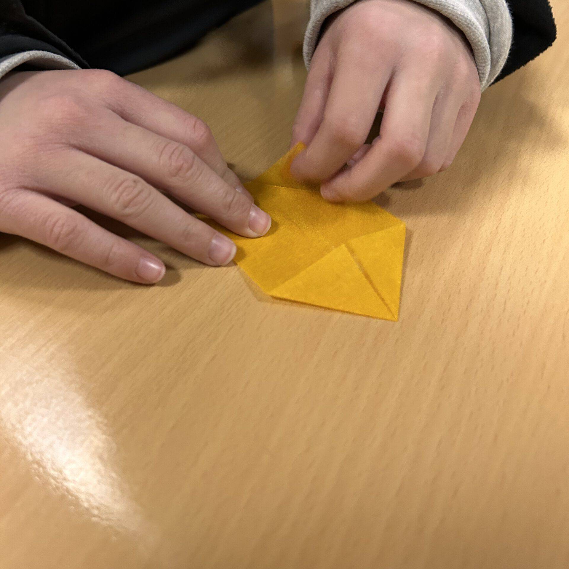 Kinderhand faltet gelben Zettel