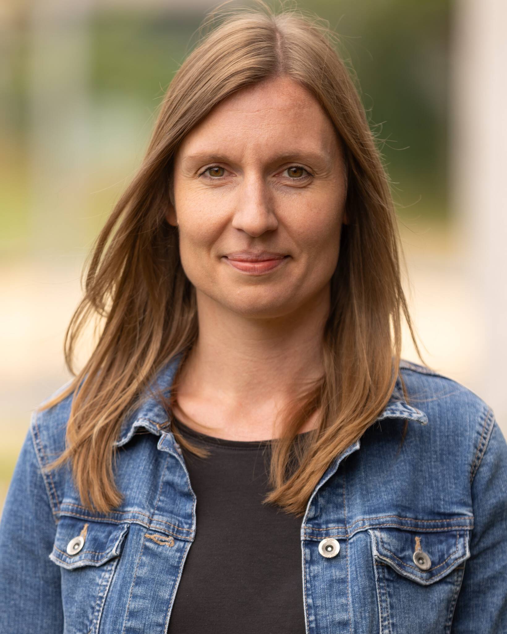Eine Frau schaut direkt in die Kamera und lächelt freundlich.